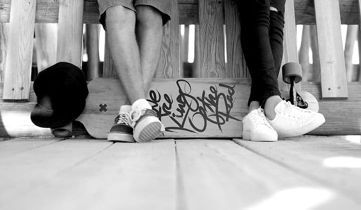 Two people sitting with a skateboard
